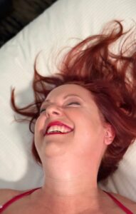 Nikki Ivana smiling on a bed during a Las Vegas lingerie photoshoot