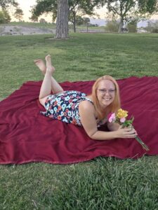 Las Vegas escort Nikki relaxing in the park with flowers on a red blanket