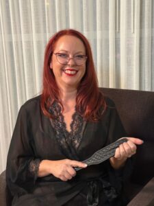 Las Vegas dominatrix holding a black spanking paddle